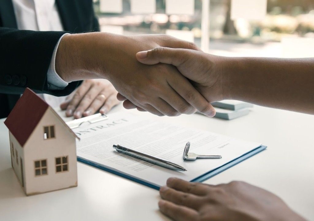 Handshake over a property contract symbolizing efficient deal management with real estate tracking software